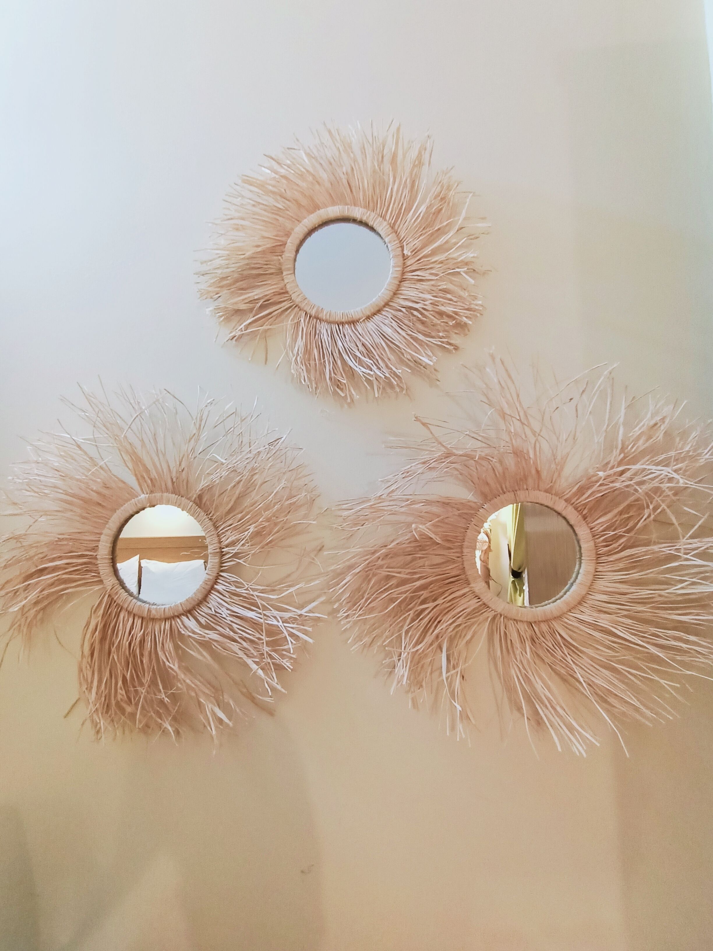 Trois miroirs muraux décorés d’un motif en forme de soleil rayonnant.