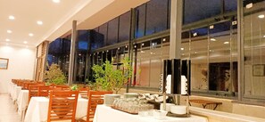 A restaurant with long tables, chairs, and a buffet area with plates and glasses. - Ceylan Hotel (Bursa)