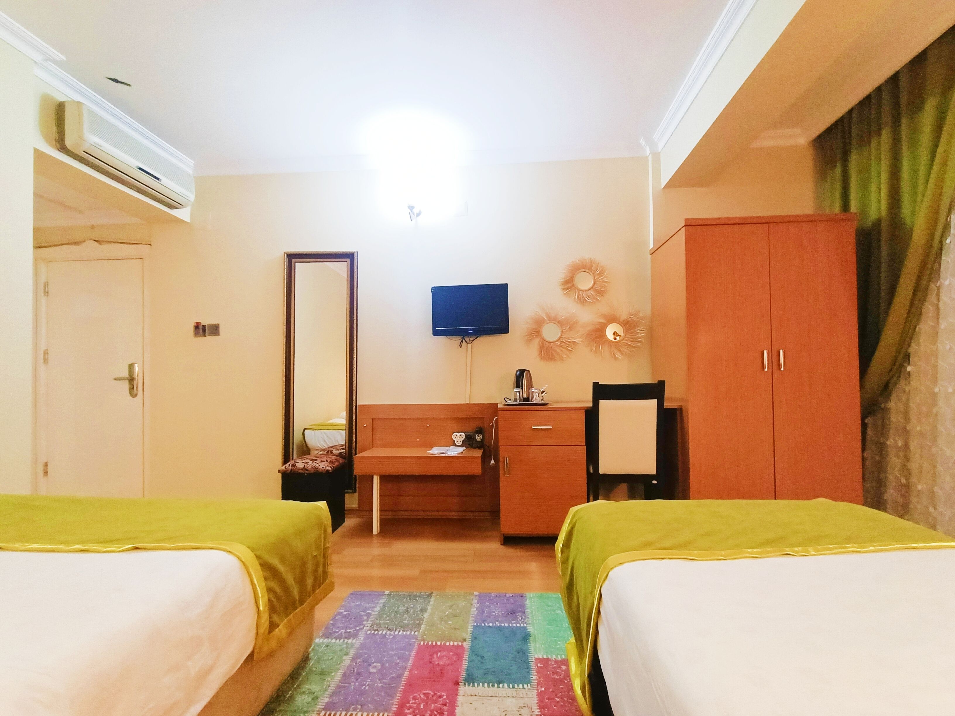 A hotel room with two beds, a desk, a television, and a wardrobe.