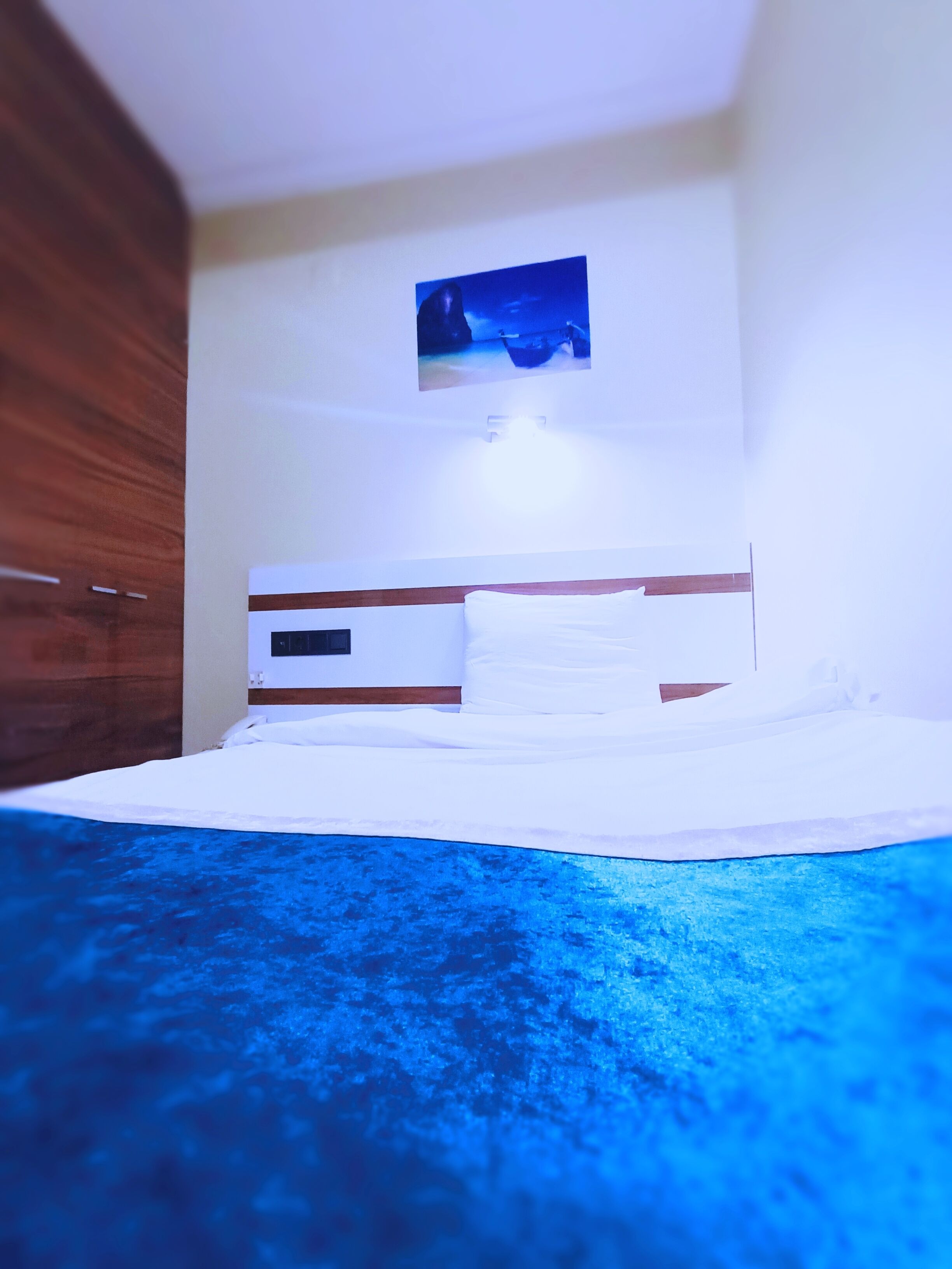 Un dormitorio con una cama, una mesita de noche y un cuadro colgado en la pared.