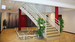 Una escalera con barandilla blanca, un pilar rojo y un pequeño jardín de rocas en la base.