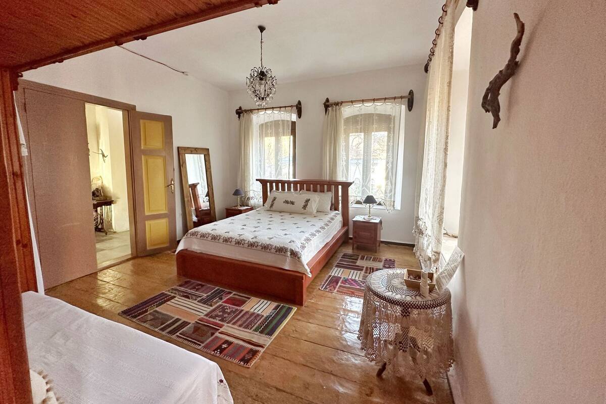 Un dormitorio con una cama de madera, una araña, un tapete estampado y una pequeña mesa redonda.