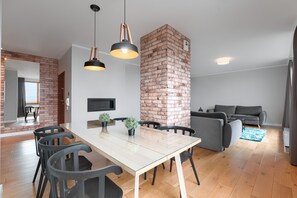Um espaço de estar moderno com área de jantar, parede decorada em tijolo e sofá cinza.