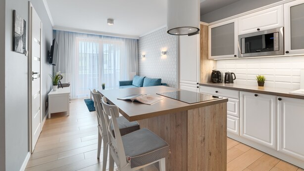 Een moderne keuken met witte kasten, een inbouwmagnetron en een houten eiland.
