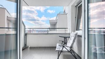 A balcony with a glass door, a small round table, and a single white chair.
