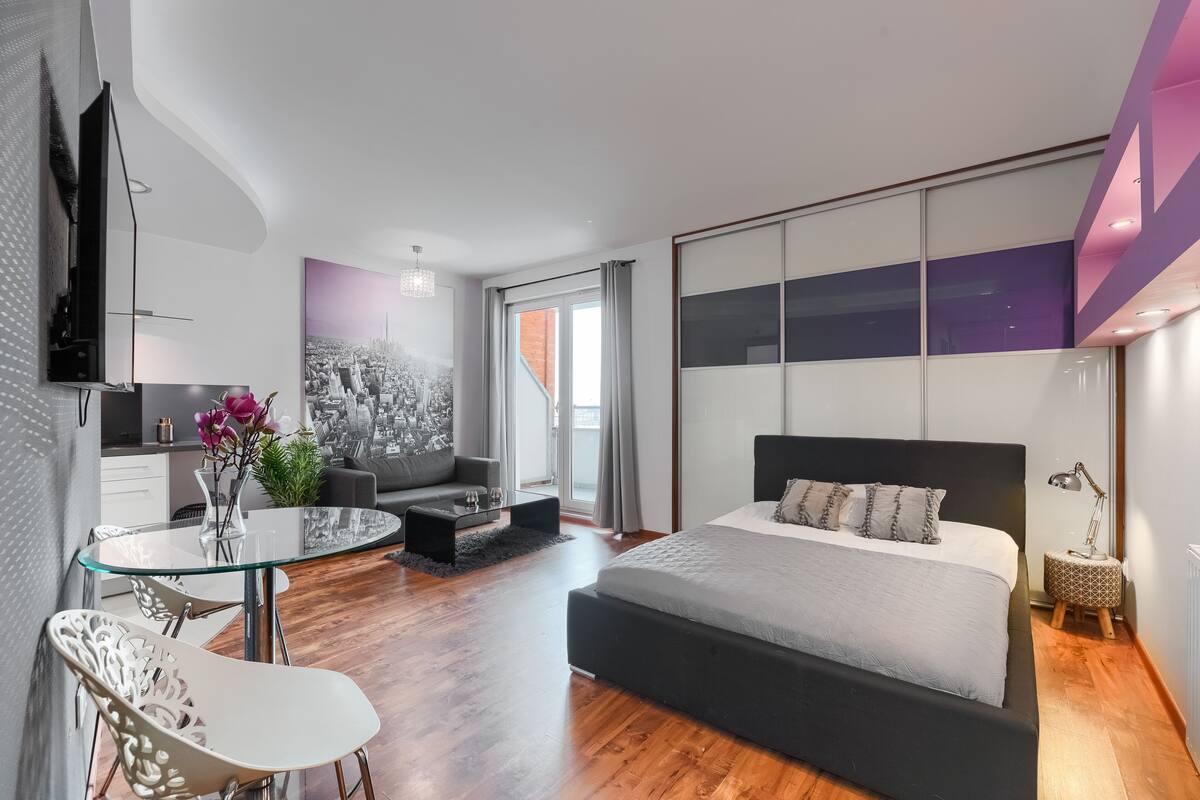 Une chambre moderne avec un grand lit, une table à manger en verre et un canapé.