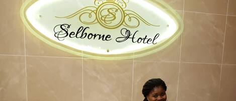 A reception desk with a sign reading "Selborne Hotel" above it.