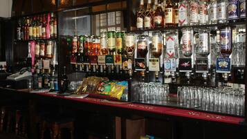A bar area with various liquor bottles, glasses, and snacks.