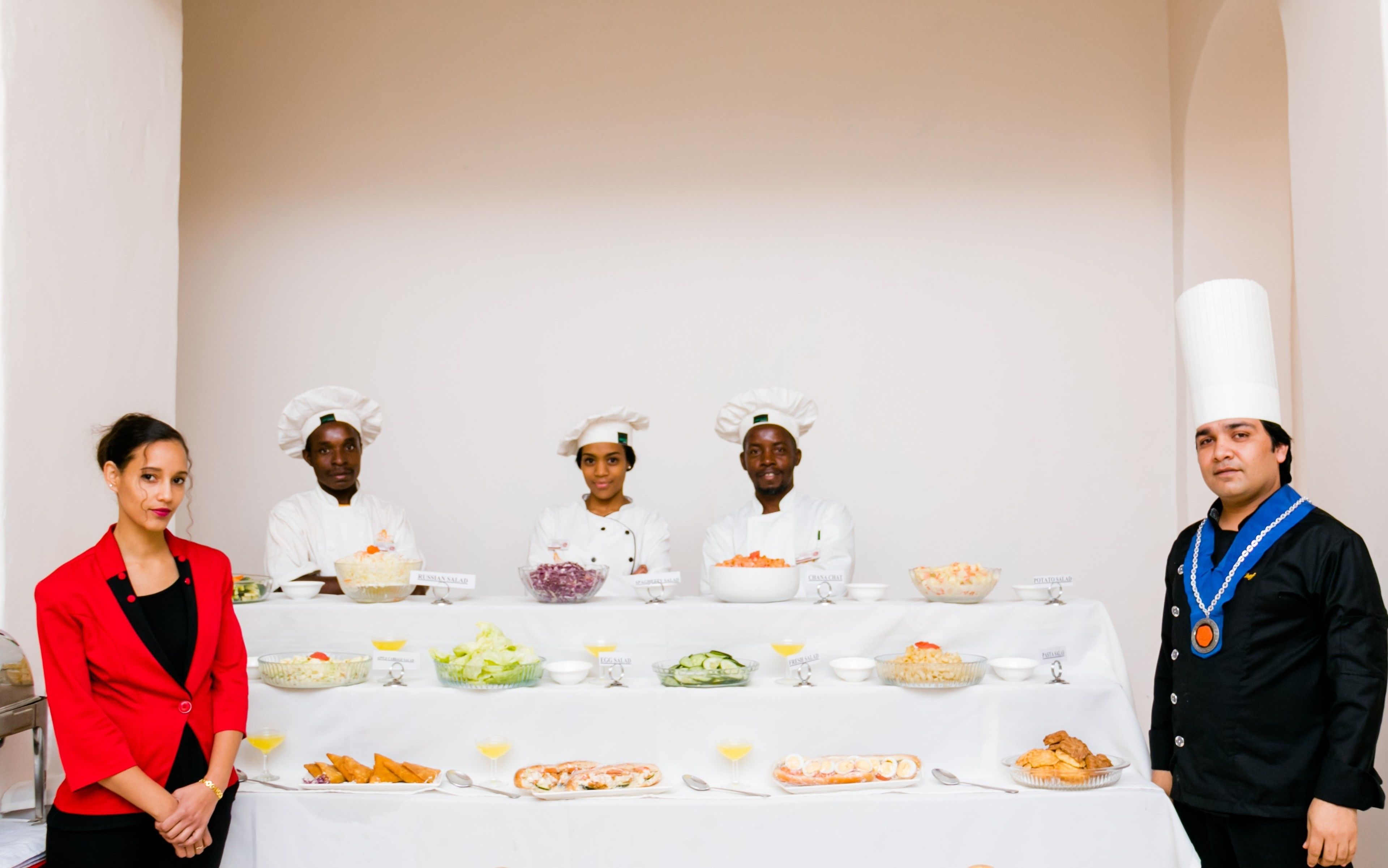 A group of chefs standing in front of a buffet table with various dishes.