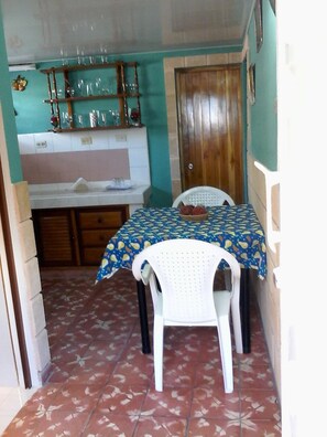 A compact kitchen area with a dining table set for meals, featuring a tiled backsplash and wooden door.
