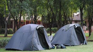 Two tents set up in a grassy area with trees and a building in the background. - Mountainview Backpackers Kisumu (Kisumu)