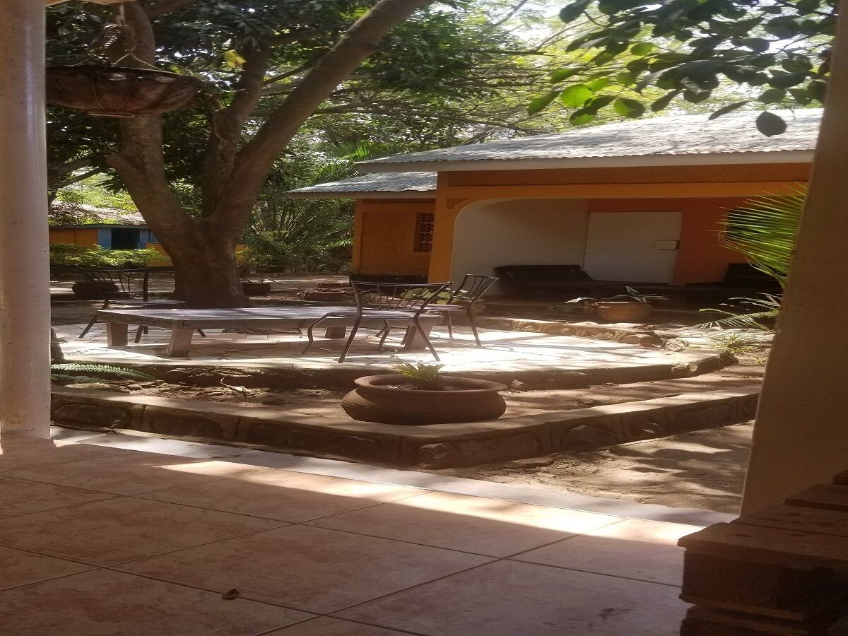 Un patio al aire libre con suelo de baldosas, una jardinera redonda y un edificio con tejado de tejas al fondo.