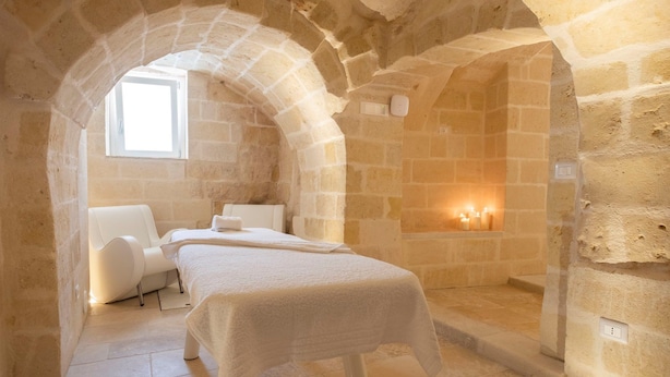 A stone-walled bedroom with a bed, a chair, and a small window. - House of Cappadocia (Ürgüp)