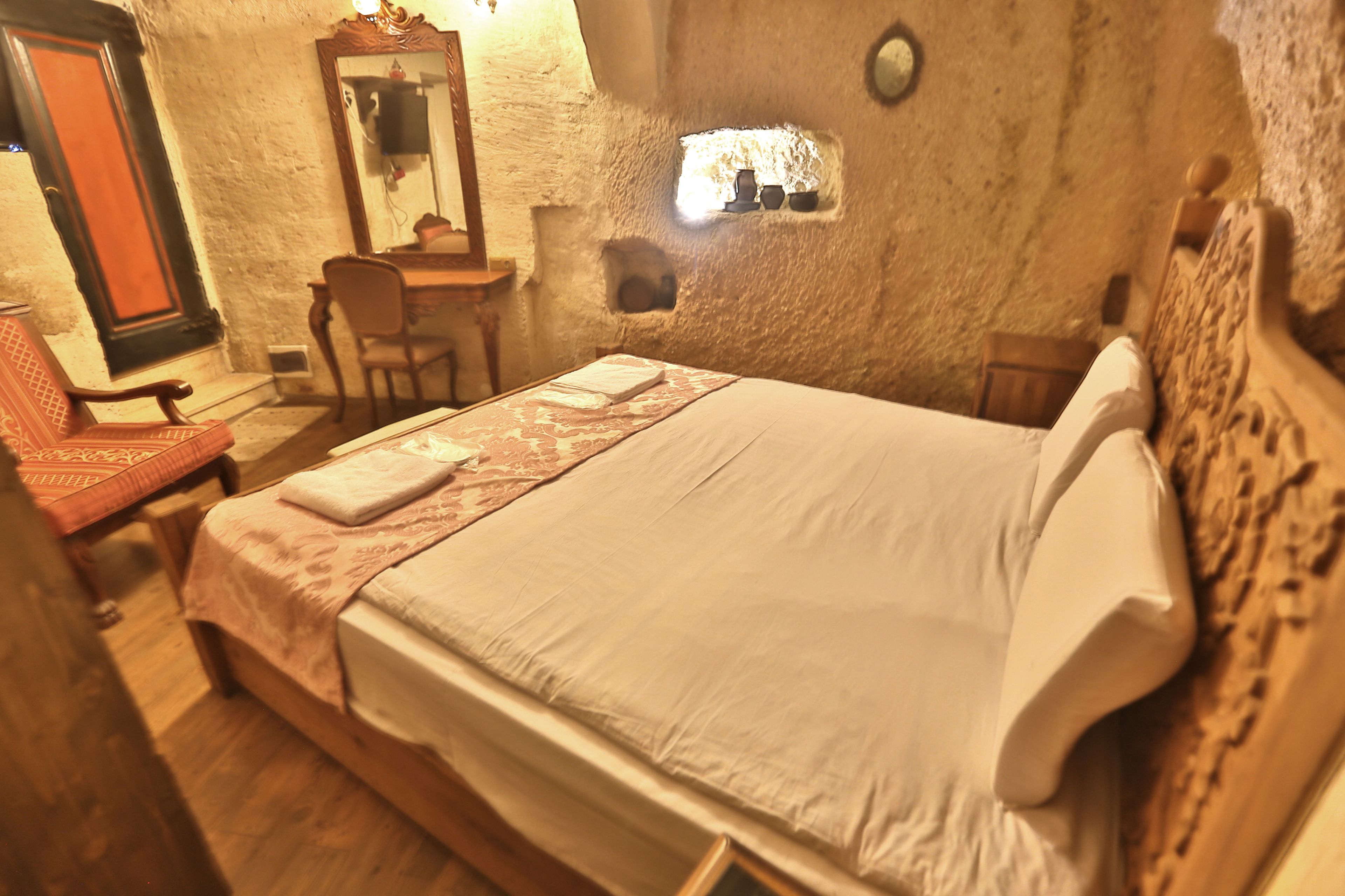 Una camera da letto con un letto grande, una testiera in legno, uno specchio, una scrivania e una sedia.