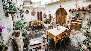 A courtyard with a wooden table and chairs, surrounded by potted plants and a chessboard. - House of Cappadocia (Ürgüp)
