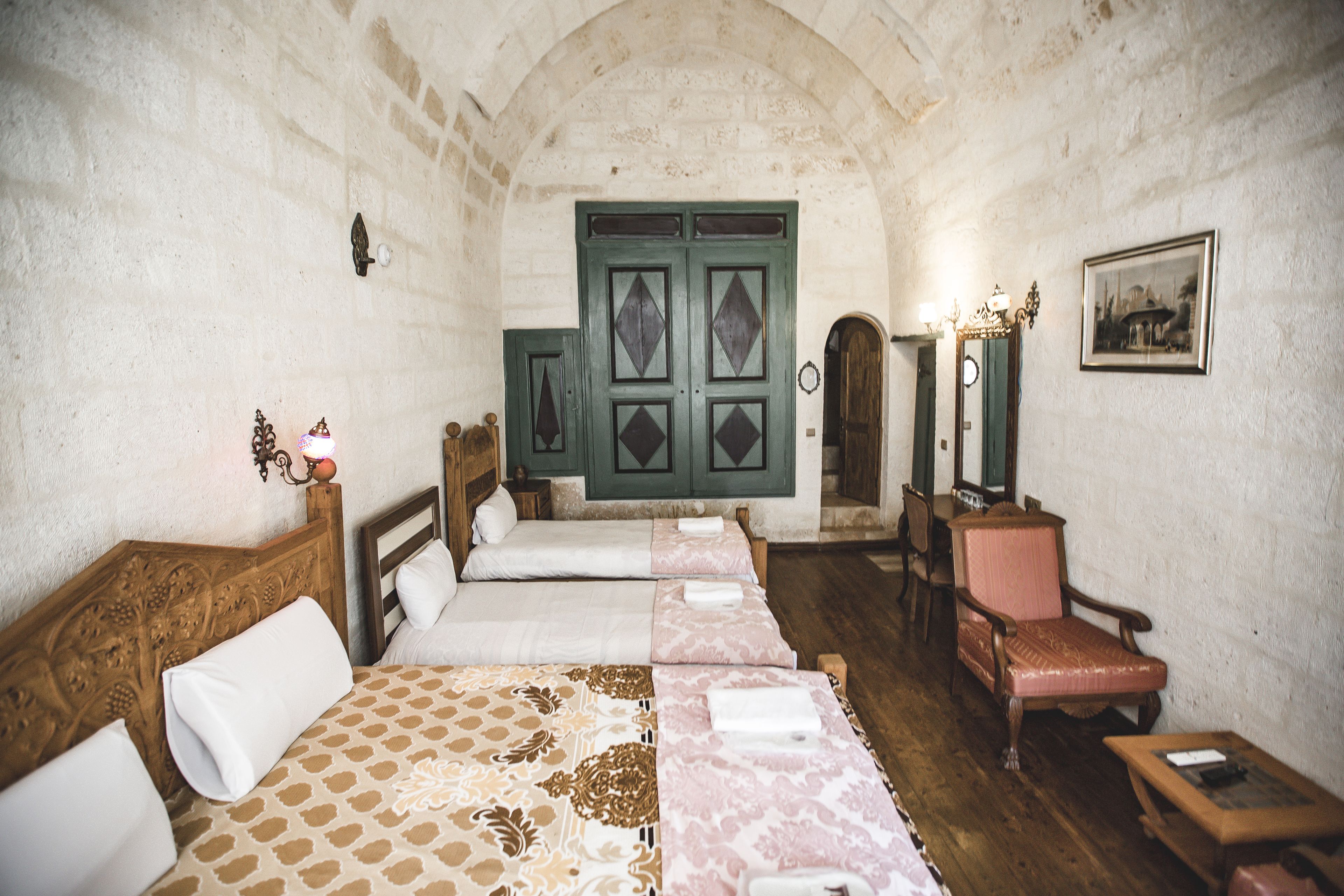 A room with two beds, a wooden chair, a small table, and a mirror.