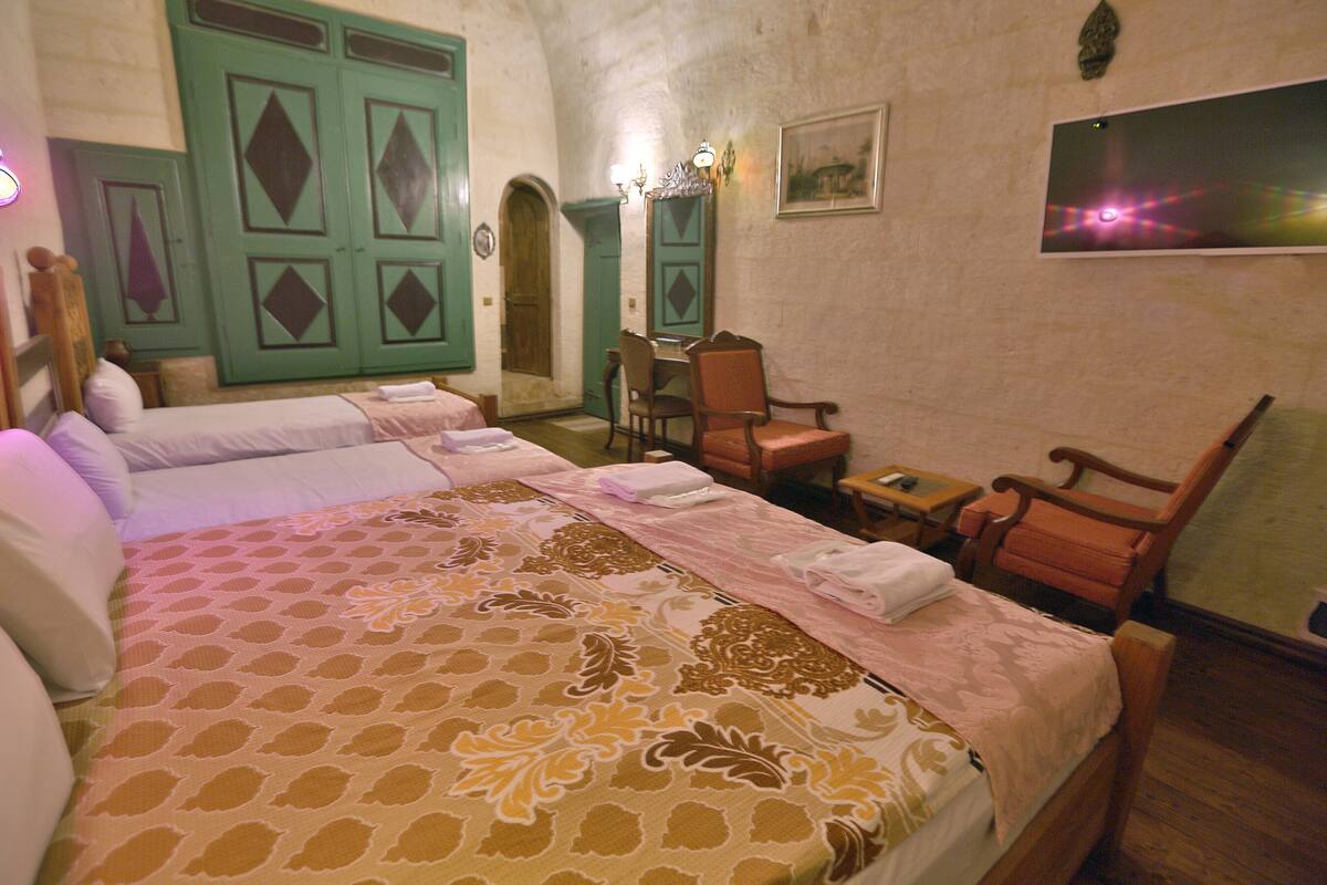 A hotel room with two beds, a small table, and a chair.