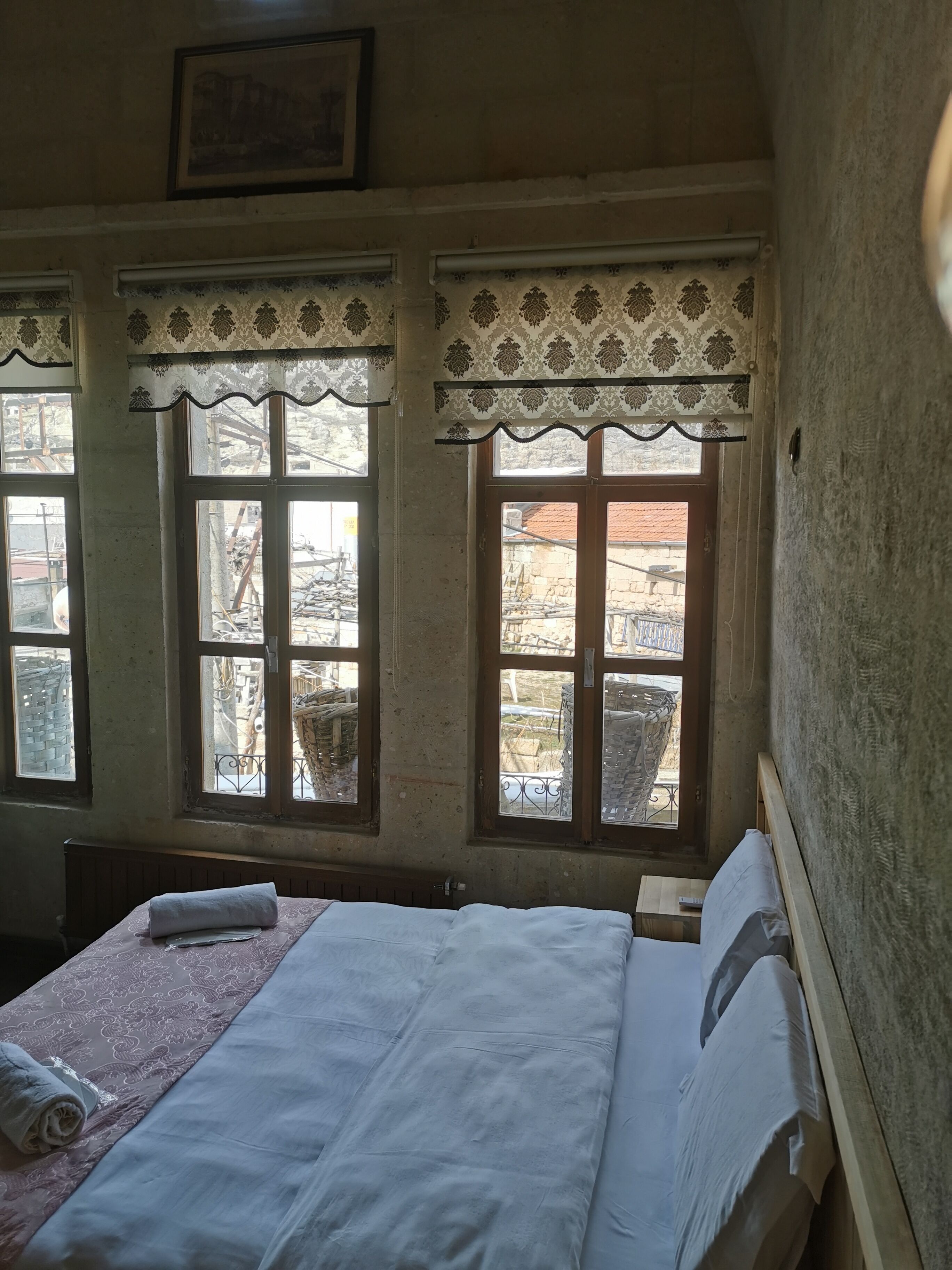 Un dormitorio con cama, ventana con vistas al exterior y cortina decorativa.