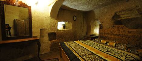 Un dormitorio rústico con una cama grande, un aparador de madera, un espejo y una pared de piedra.