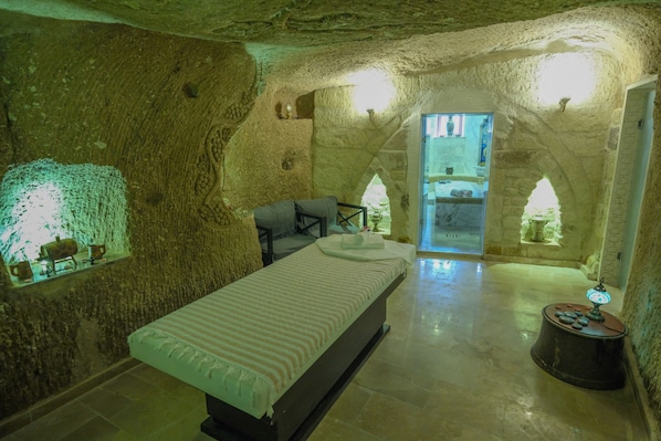 A room with a bed, a small table with a lamp, and a window.