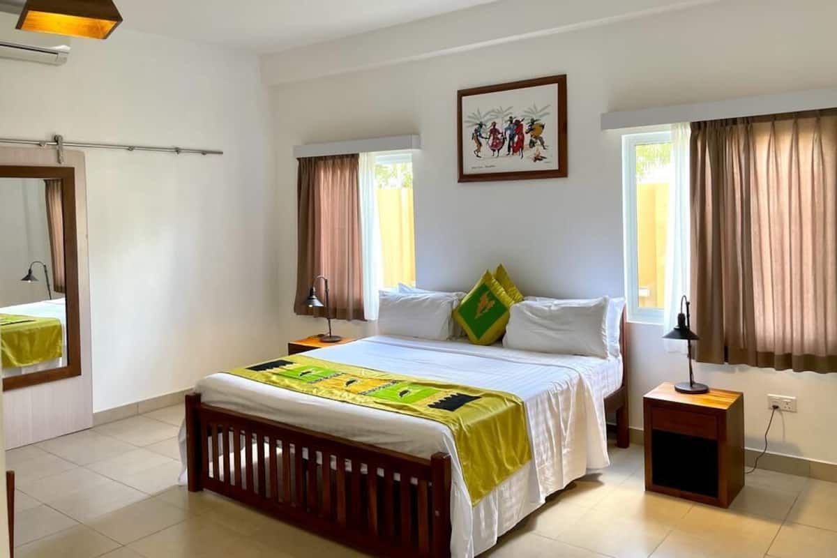A bedroom with a bed, bedside tables, a mirror, and a window with curtains.