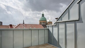 Una terrassa a la teulada amb vista a una església amb cúpula verda i campanar.