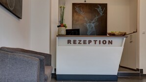 Un taulell de recepció amb un senyal que diu "RECEPTION" i una obra d'art de corçó emmarcada a sobre.