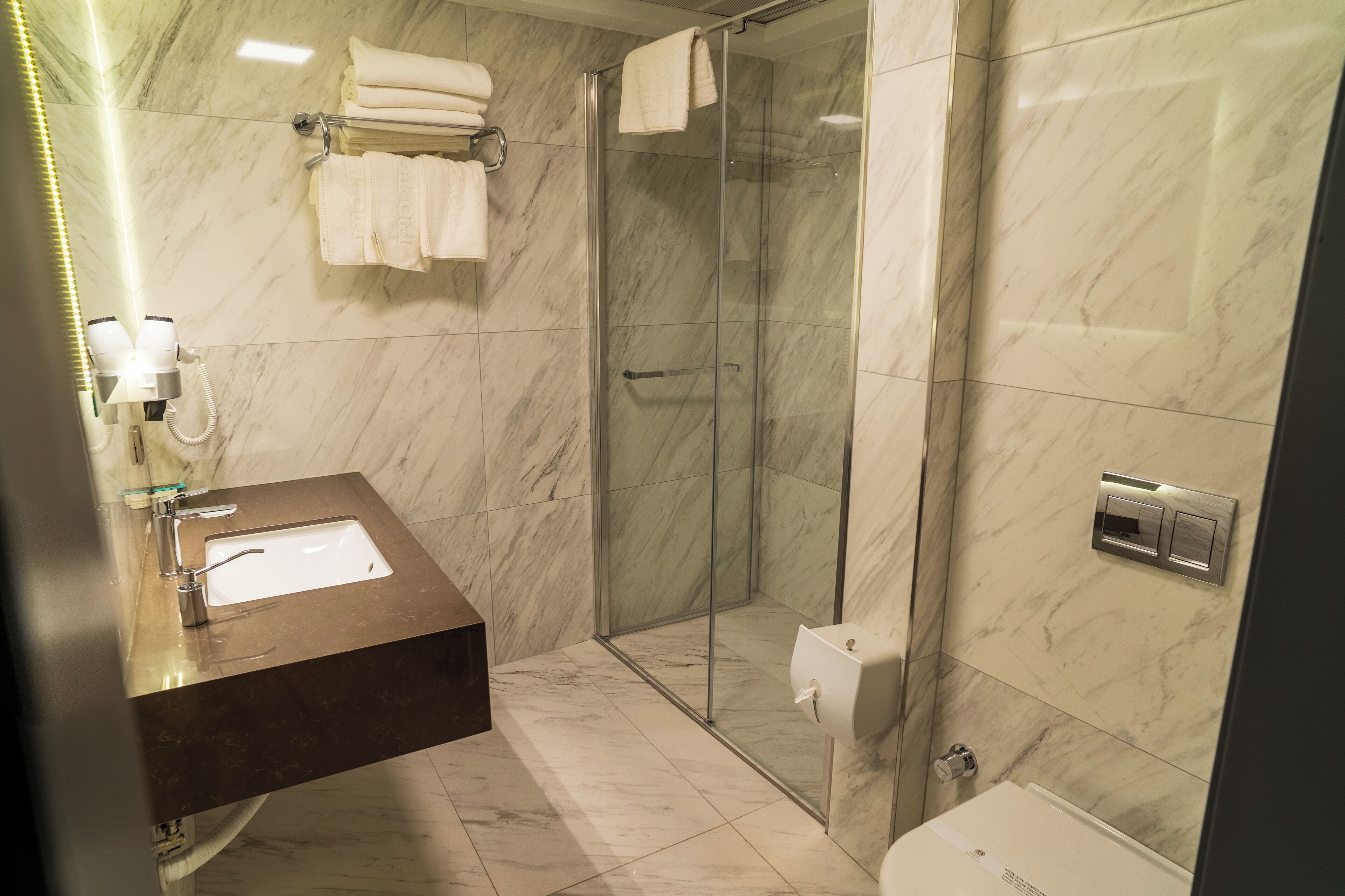 Ein Badezimmer mit Marmorwaschbecken, einer Duschkabine aus Glas und einer Toilette.