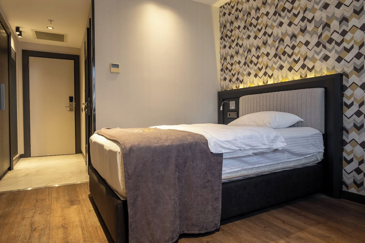 A hotel room with a bed, a door, and a patterned wall.