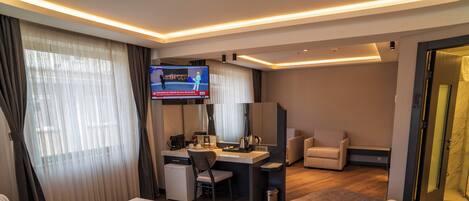 A hotel room with a bed, desk, chair, TV, and curtains.
