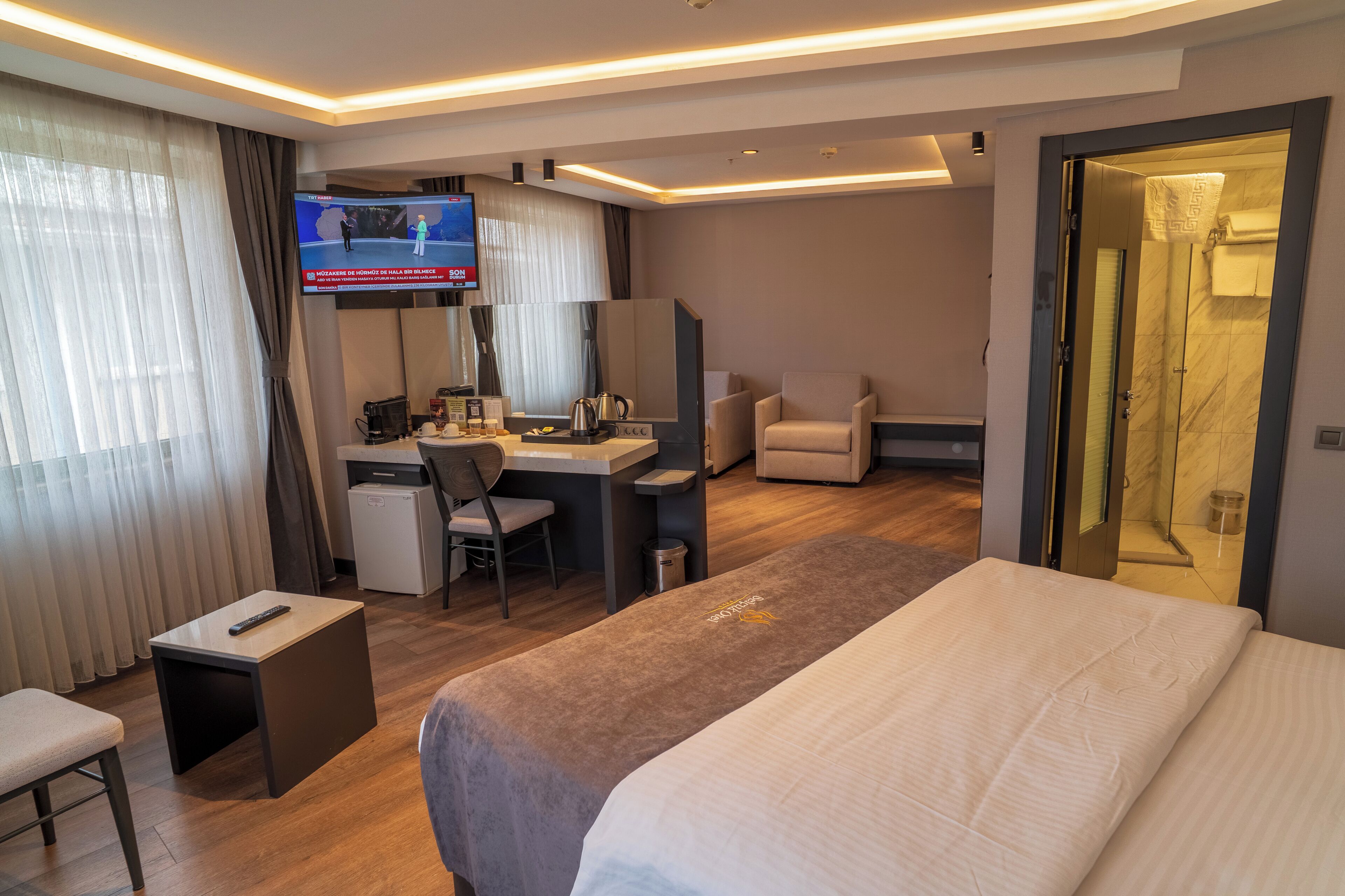 Une chambre d’hôtel équipée d’un lit, d’un bureau, d’une chaise, d’une télévision et d’un espace douche.