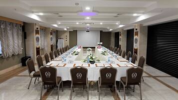 A conference room with a long table, chairs, and a projector screen.