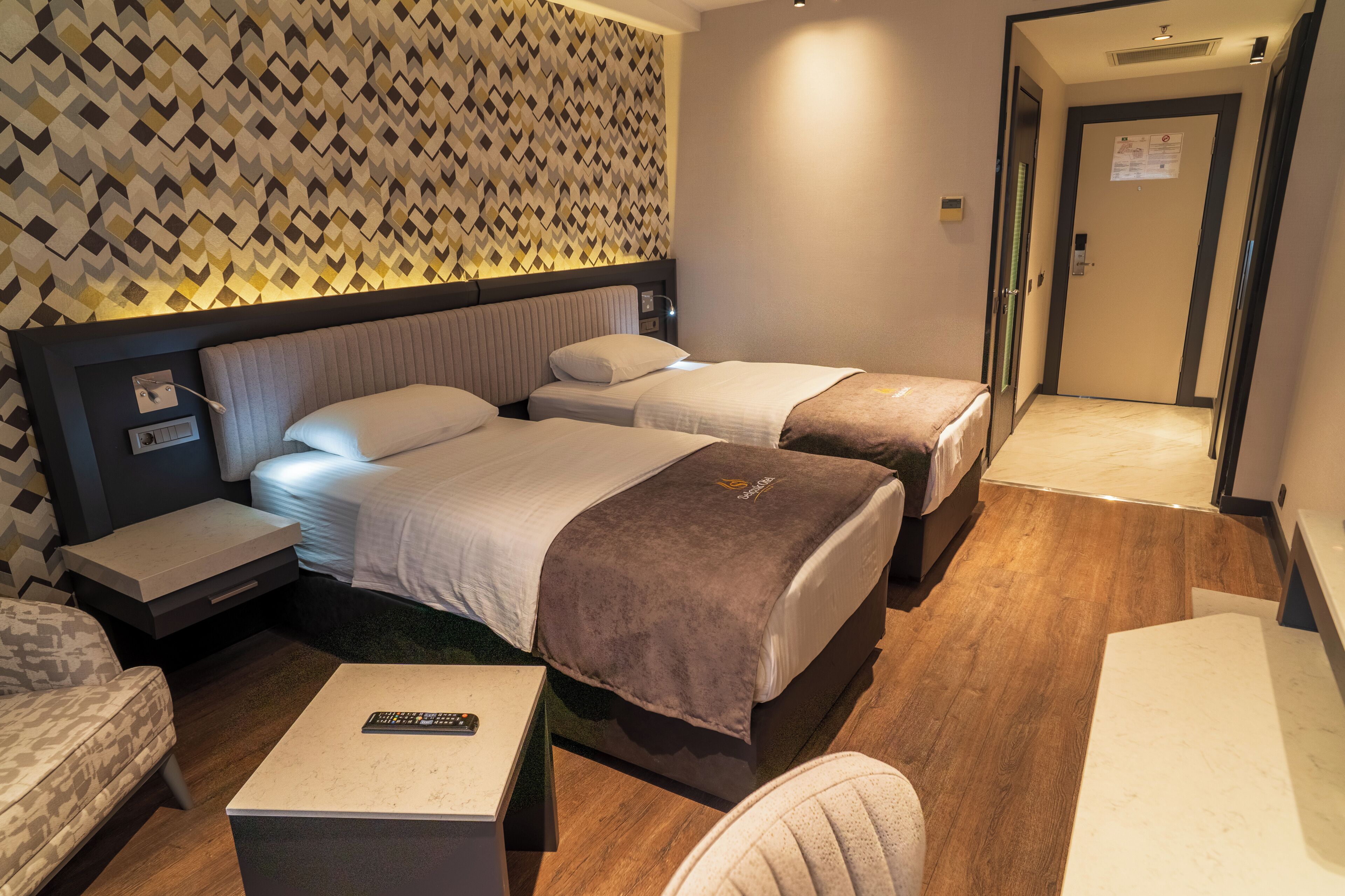 Ein Hotelzimmer mit zwei Betten, einem kleinen Tisch, einem Stuhl und einer Wand mit Muster.