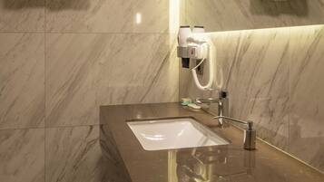 A modern bathroom with a marble floor, a black countertop, a sink, a mirror, and towel racks.