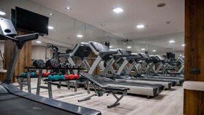 Un gimnasio con cintas de correr, bancos de pesas y mancuernas.