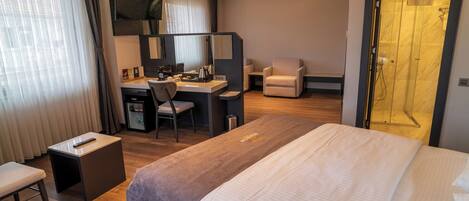 A hotel room with a bed, desk, chair, and a shower area.