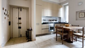 Cozinha moderna com área de refeições, com mesa e cadeiras de madeira, forno embutido e janela que proporciona iluminação natural.