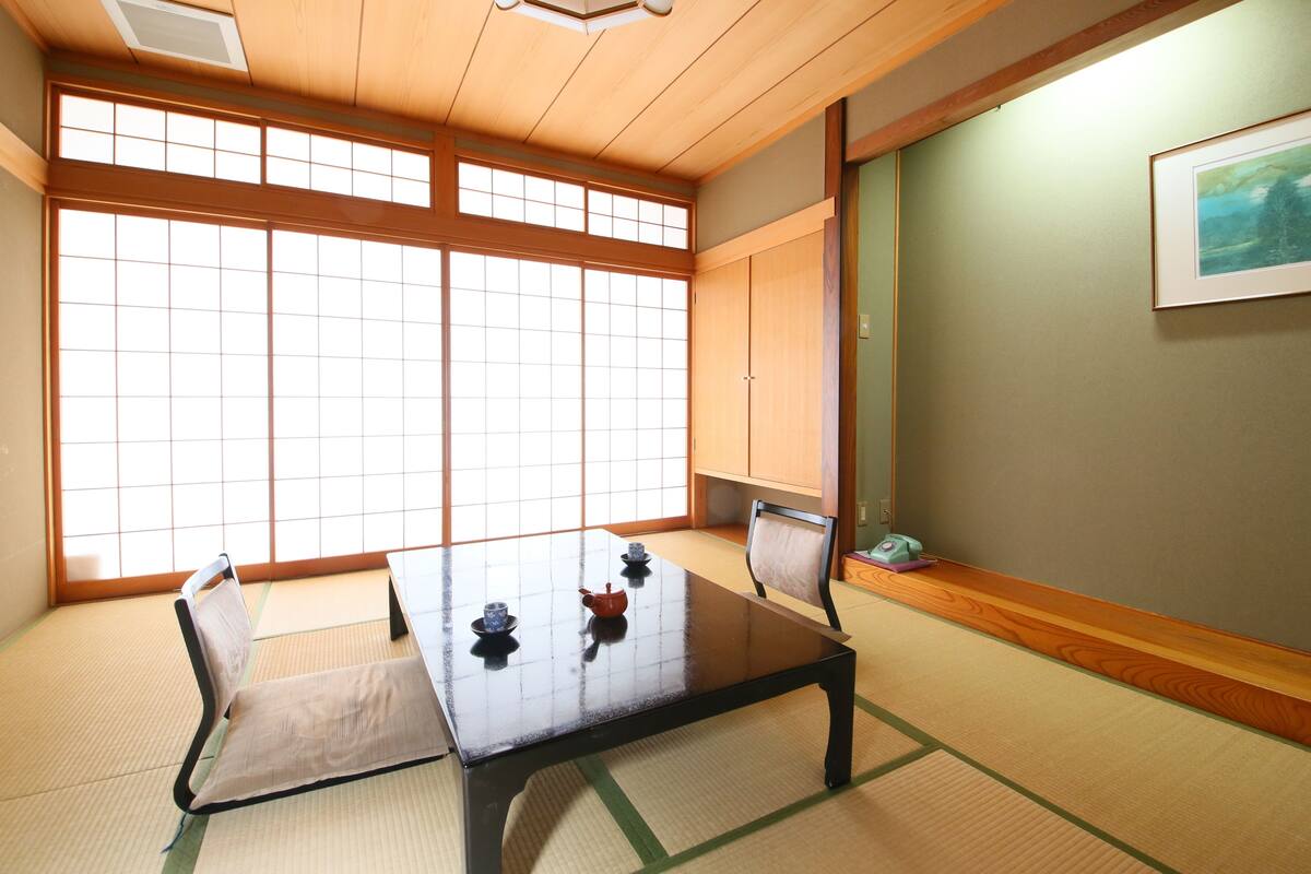 Una habitación japonesa tradicional con suelo de tatami, una mesa baja y puertas correderas.