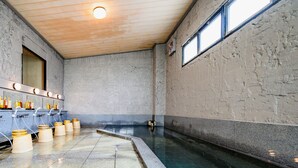 A large indoor pool with a wooden ceiling and stone walls. There are multiple sinks with mirrors and bottles on the left side. - Ogiwarakan (Chikuma)