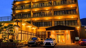 A multi-story hotel with a central entrance, balconies on each floor, and several parked cars in front. - Ogiwarakan (Chikuma)
