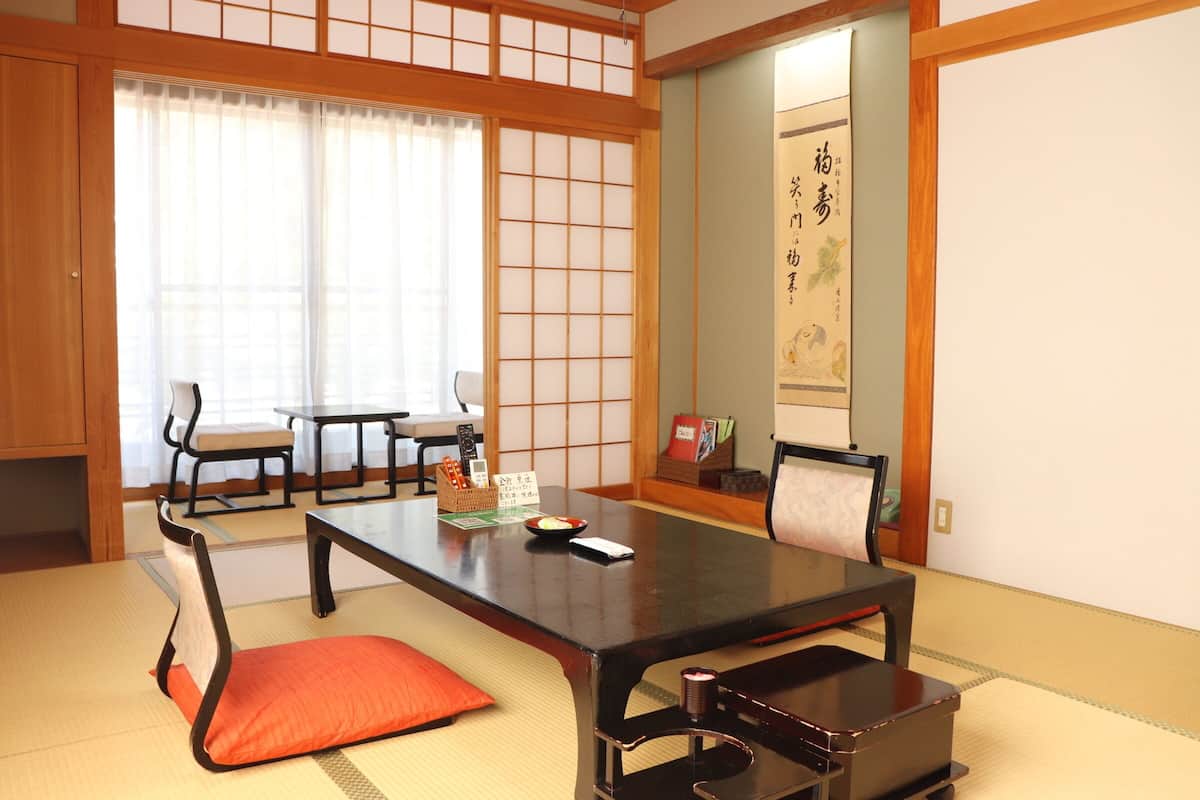 Una habitación japonesa tradicional con suelo de tatami, una mesa baja y dos sillas.