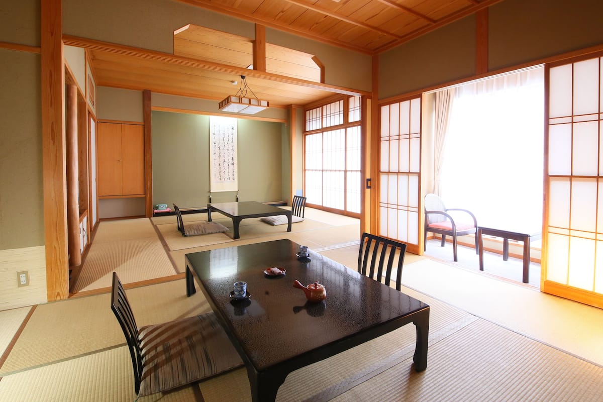 Una habitación japonesa tradicional con suelo de tatami, una mesa baja y puertas correderas.