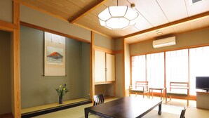 A traditional Japanese room with tatami flooring, a low table, wooden chairs, a TV, and a large window. - Ogiwarakan (Chikuma)