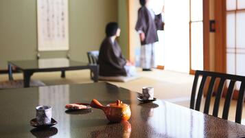 A traditional Japanese room with tatami flooring, a low table with tea set, and a sliding door.