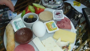 A plate with various food items including a croissant, ham, cheese, and condiments. - Taksim Palace Hotel (Istanbul)