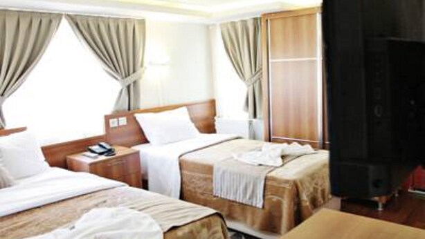 A hotel room with two beds, a TV, and a wooden desk. - Taksim Palace Hotel (Istanbul)
