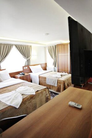 A hotel room with two beds, a TV, and a wooden desk. - Taksim Palace Hotel (Istanbul)