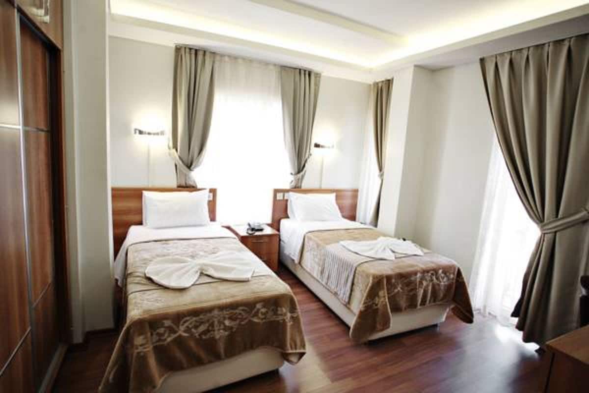 A hotel room with two single beds, wooden headboards, and a nightstand between them.