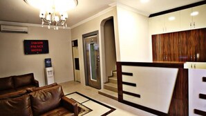 A hotel lobby with a brown leather sofa, a chandelier, a reception desk, and a sign that reads "Taksim Palace Hotel". - Taksim Palace Hotel (Istanbul)