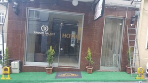 The exterior of Taksim Palace Hotel with a large glass entrance, potted plants, and a doormat with the hotel’s logo. - Taksim Palace Hotel (Istanbul)